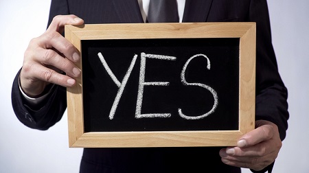 The word yes written on blackboard being held by a businessman. Credit: https://www.istockphoto.com/portfolio/Motortion