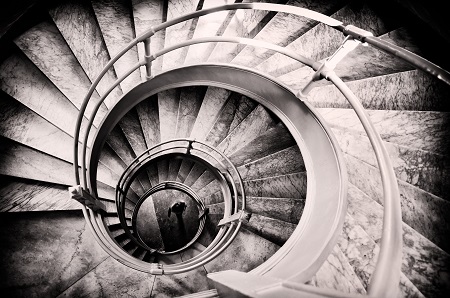 A staircase descending into a downward spiral towards darkness