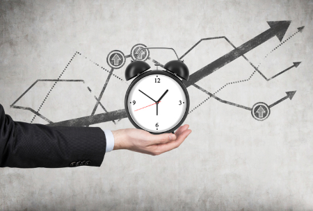 Man holding a clock with a background of time series graphs. Credit: ismagilov