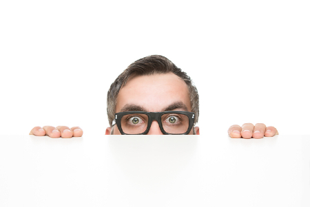 Fearful executive peaking over a desk. Credit: https://www.istockphoto.com/au/portfolio/nastco