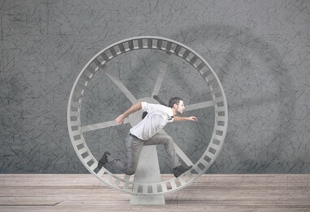 Male employee running on a hamster wheel.