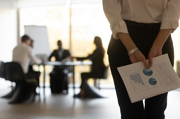 A woman holding a KPI report behind her back as she hesitates to join a meeting. Credit: https://www.istockphoto.com/portfolio/fizkes